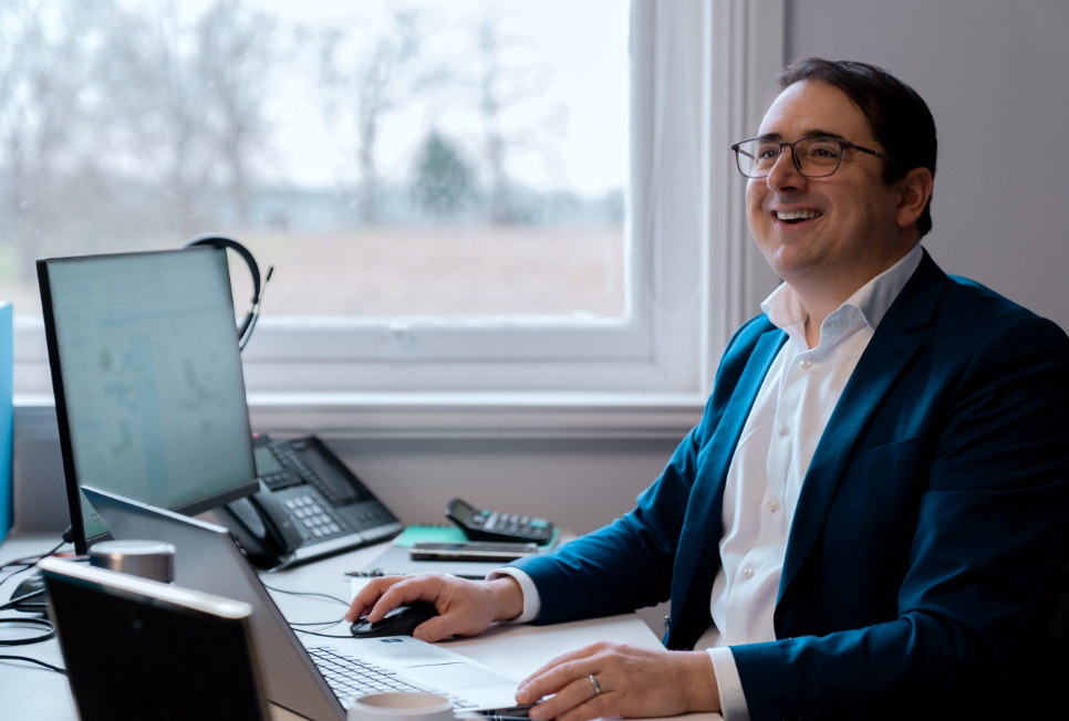 Image of a regional manager smiling at his desk whilst using his laptop