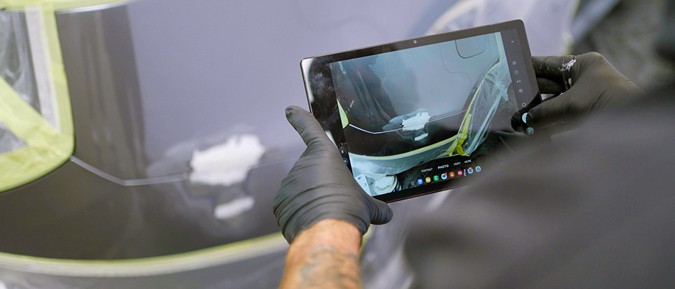 AI-Enhanced Systems Close up of technicians hands taking photo of vehicle repair on his tablet